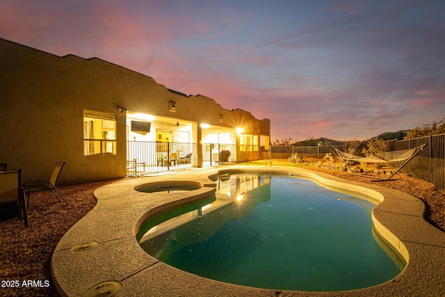 pool at dusk featuring an in ground hot tub and a patio