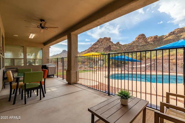 view of patio / terrace featuring a fenced in pool, ceiling fan, and a mountain view