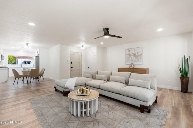 living room with light wood-style flooring, baseboards, ceiling fan, and recessed lighting