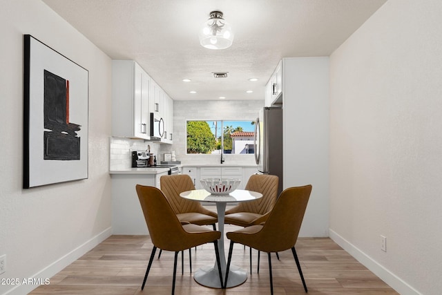 dining area with light wood finished floors, visible vents, baseboards, and recessed lighting