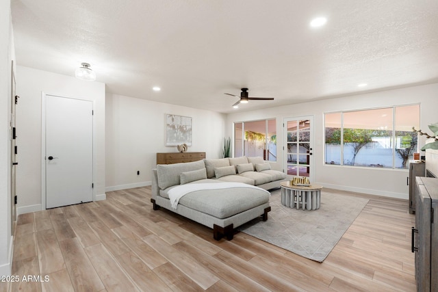 living area featuring a textured ceiling, light wood finished floors, recessed lighting, and baseboards