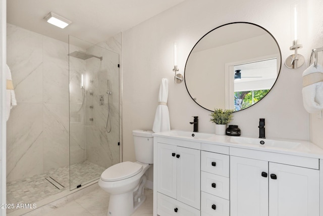 bathroom with a marble finish shower, double vanity, a sink, and toilet