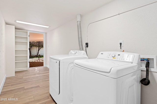 laundry area with baseboards, laundry area, light wood-style flooring, and washer and dryer