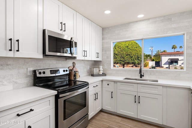 kitchen with stainless steel appliances, a sink, light countertops, and decorative backsplash