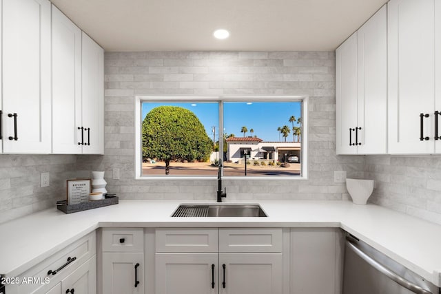 kitchen with stainless steel dishwasher, white cabinetry, and a sink