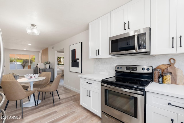 kitchen featuring tasteful backsplash, stainless steel appliances, light countertops, light wood-type flooring, and white cabinetry