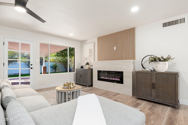 living room featuring baseboards, visible vents, a glass covered fireplace, wood finished floors, and recessed lighting