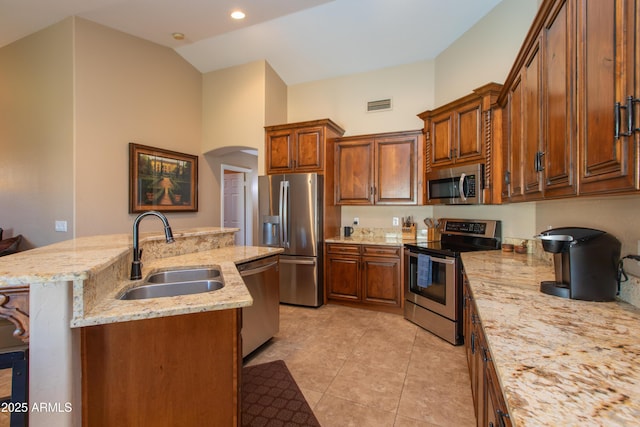 kitchen with an island with sink, a breakfast bar area, appliances with stainless steel finishes, light stone counters, and sink