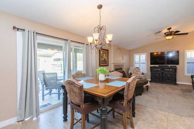 dining space featuring light colored carpet, vaulted ceiling, plenty of natural light, and ceiling fan with notable chandelier