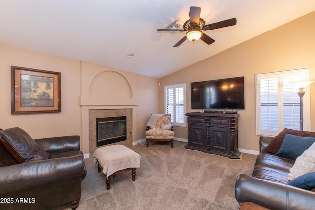 living room featuring ceiling fan, a tiled fireplace, vaulted ceiling, and carpet flooring