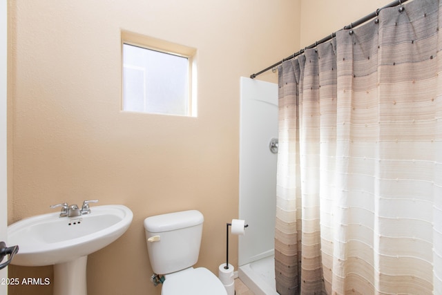 bathroom with toilet, sink, and curtained shower