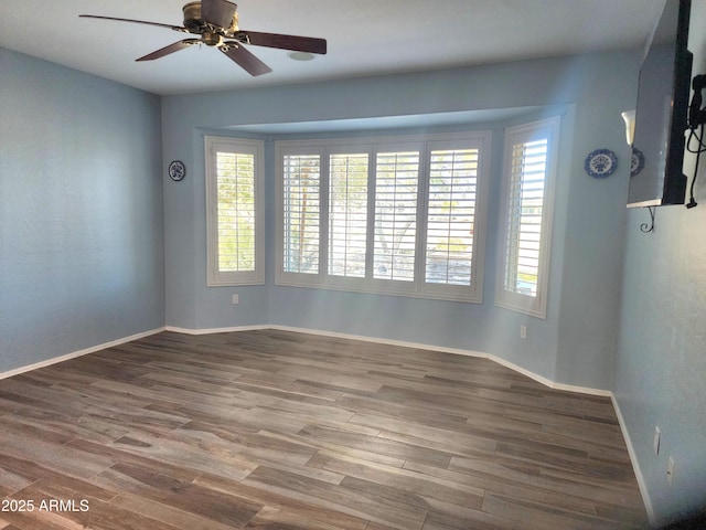 spare room featuring wood finished floors, a ceiling fan, and baseboards