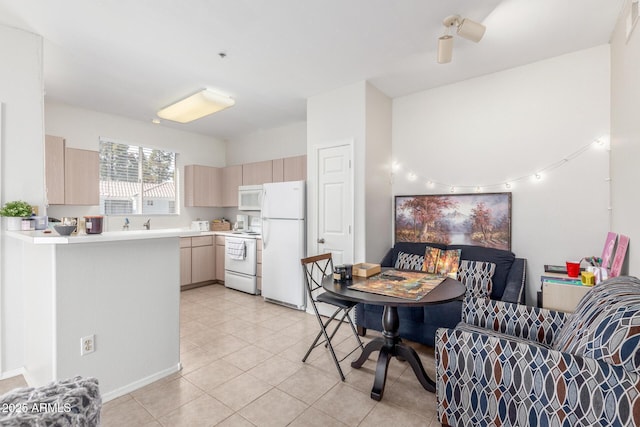 kitchen featuring kitchen peninsula, light brown cabinetry, white appliances, and light tile patterned flooring