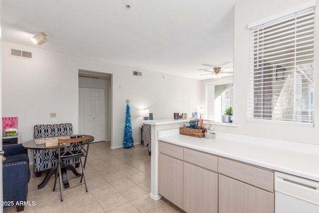 kitchen with kitchen peninsula, white dishwasher, ceiling fan, light brown cabinets, and light tile patterned floors