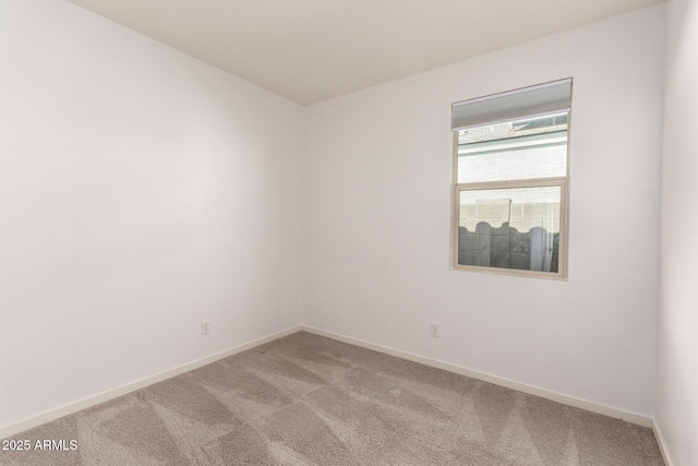 empty room featuring light carpet and baseboards