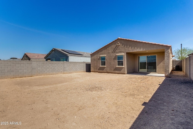 rear view of property featuring stucco siding, a fenced backyard, and a tile roof