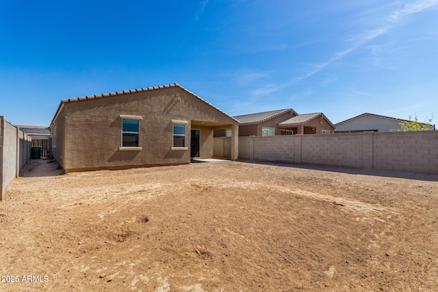 rear view of house featuring a tile roof, a fenced backyard, and stucco siding