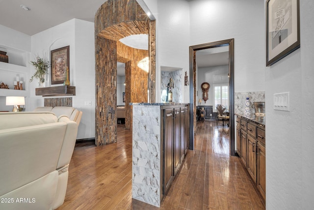 kitchen with built in features, dark stone counters, open floor plan, dark wood-style flooring, and a high ceiling