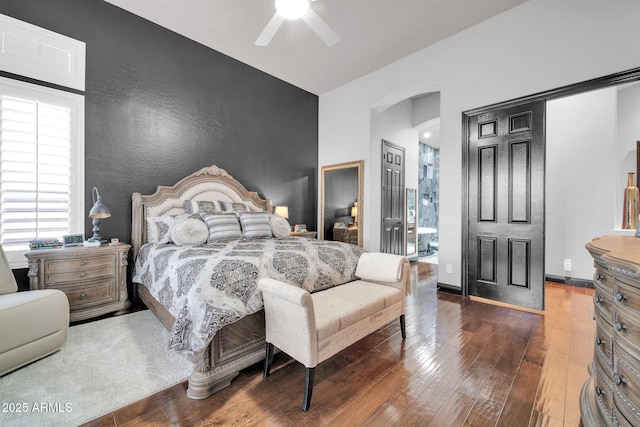 bedroom featuring arched walkways, baseboards, ceiling fan, and hardwood / wood-style floors