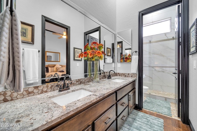 full bathroom featuring toilet, a marble finish shower, a sink, and wood finished floors