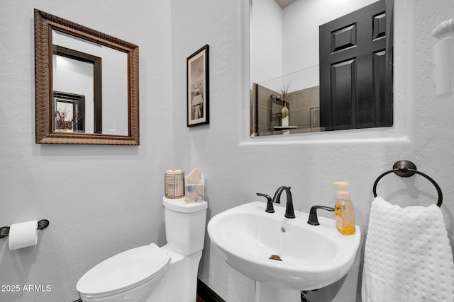 bathroom featuring a textured wall, a sink, and toilet