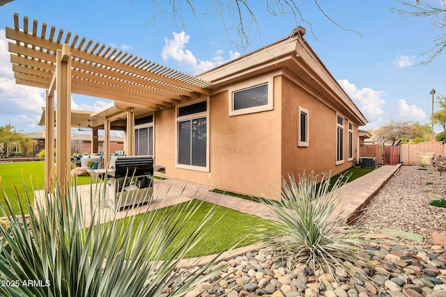 back of house featuring stucco siding, a patio area, central AC, a pergola, and a fenced backyard