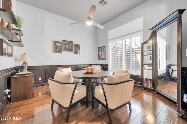 dining space with visible vents, a ceiling fan, a wainscoted wall, wood-type flooring, and breakfast area