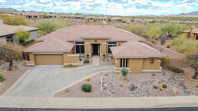 view of front facade with driveway, a tile roof, an attached garage, a mountain view, and stucco siding