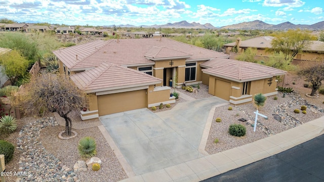 view of front of house with an attached garage, a tile roof, a mountain view, and stucco siding