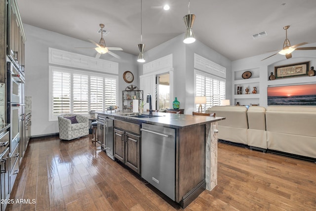 kitchen with dark countertops, visible vents, open floor plan, a sink, and dishwasher