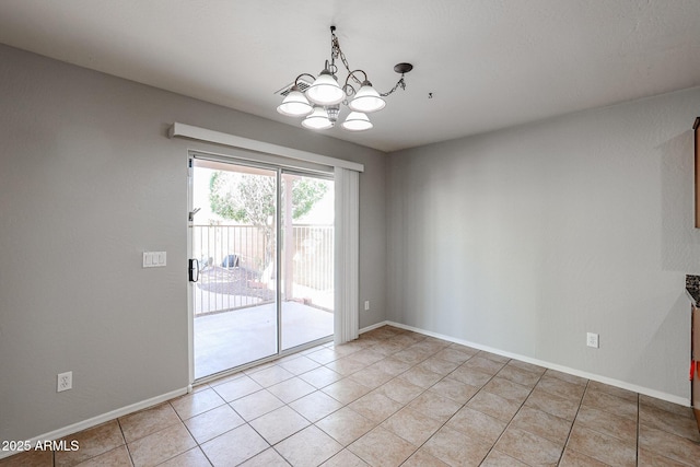 empty room featuring a chandelier, light tile patterned floors, and baseboards