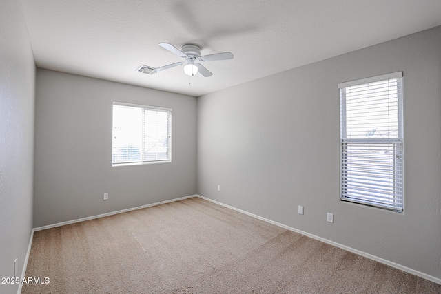 spare room featuring baseboards, light colored carpet, visible vents, and ceiling fan