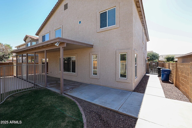 rear view of property featuring a patio area, stucco siding, and fence