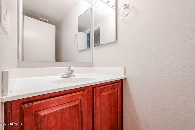 bathroom with vanity and a textured wall