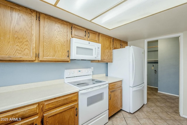 kitchen featuring light tile patterned floors, white appliances, and light countertops