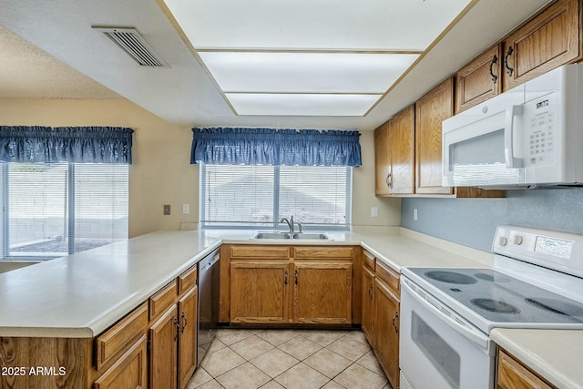 kitchen featuring a sink, visible vents, white appliances, and light countertops