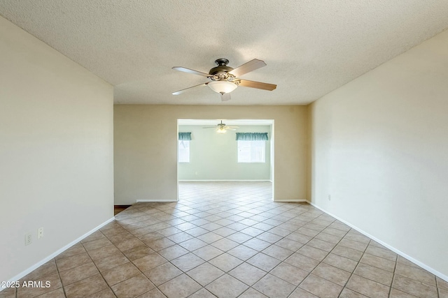 spare room featuring light tile patterned flooring, ceiling fan, a textured ceiling, and baseboards