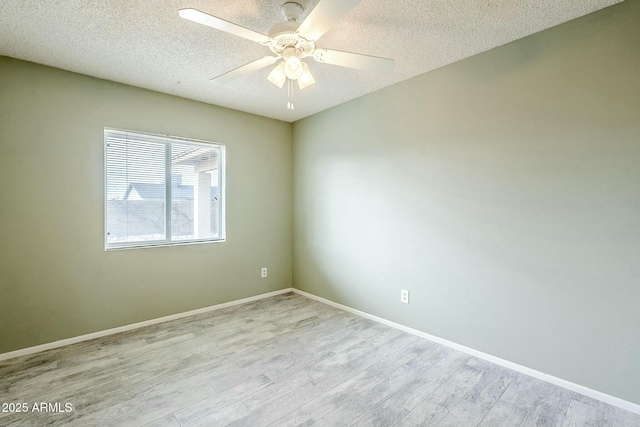 empty room with a ceiling fan, wood finished floors, baseboards, and a textured ceiling