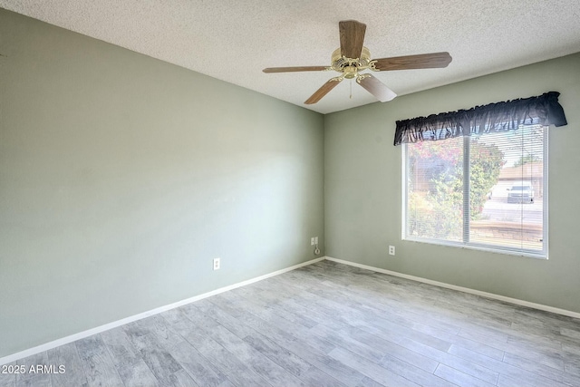 unfurnished room featuring a ceiling fan, wood finished floors, baseboards, and a textured ceiling