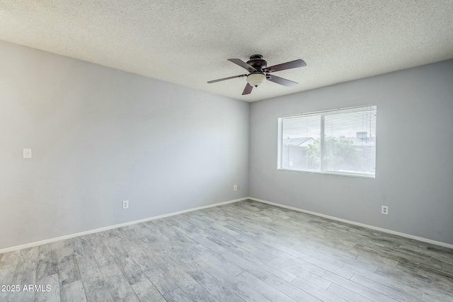 empty room with a ceiling fan, wood finished floors, baseboards, and a textured ceiling