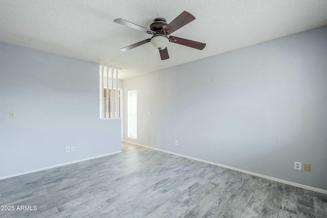 empty room with ceiling fan, wood finished floors, baseboards, and a textured ceiling