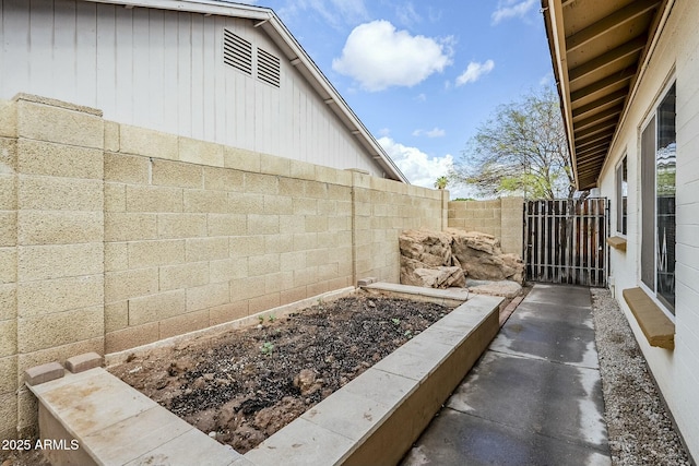 exterior space featuring a garden, a fenced backyard, and a gate