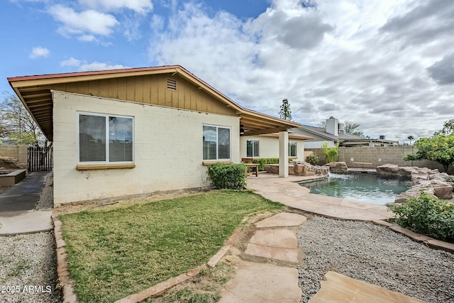 rear view of property featuring a fenced in pool, a yard, a fenced backyard, a patio area, and brick siding