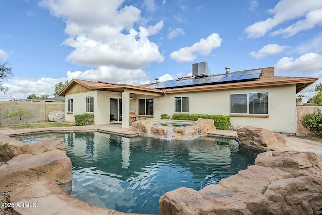 back of property with roof mounted solar panels, a fenced in pool, an in ground hot tub, and a fenced backyard