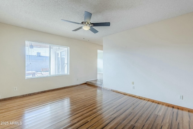 empty room featuring ceiling fan, a textured ceiling, baseboards, and wood finished floors