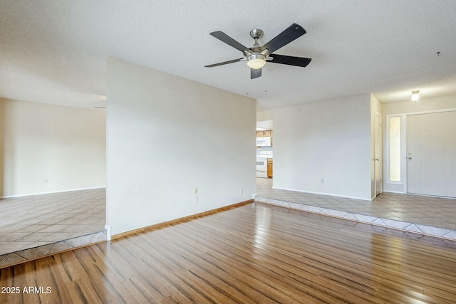 empty room with a textured ceiling, wood finished floors, and a ceiling fan