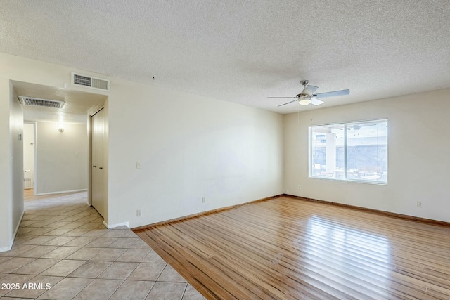 unfurnished room with visible vents, light wood finished floors, and a textured ceiling