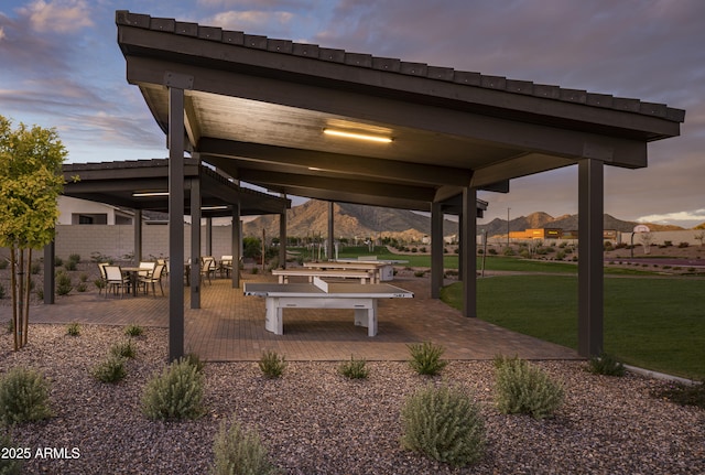 patio terrace at dusk with a gazebo, a mountain view, and a yard