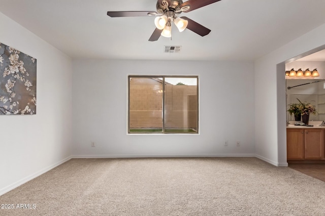 carpeted spare room with baseboards, ceiling fan, and visible vents