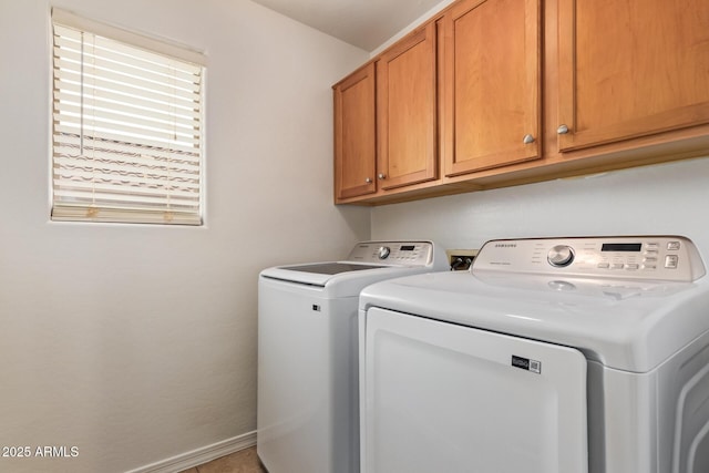 laundry room featuring washing machine and clothes dryer, cabinet space, and baseboards